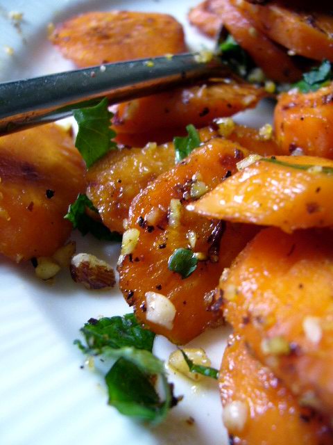 Carottes croustillantes au jus d'orange agrémentées de feuilles de menthe et de coriandre. Pour la touche croquante, des noisettes concassées. 