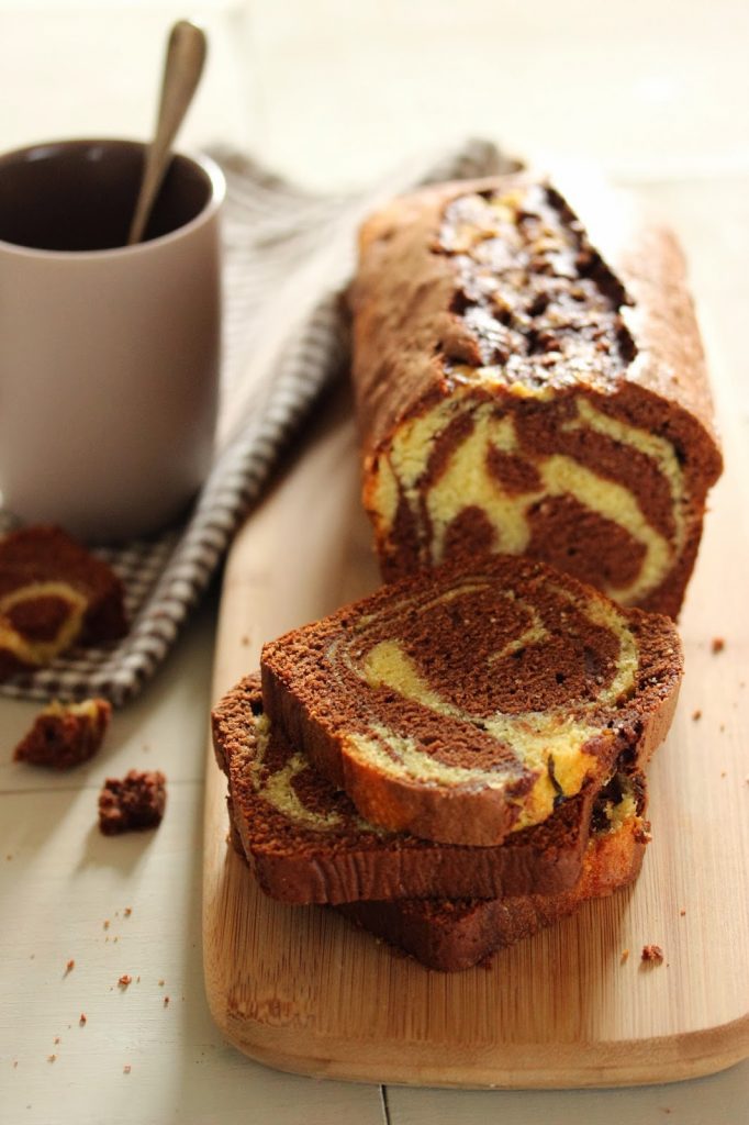 Gâteau marbré vanille et chocolat coupé en tranches et posé sur une planche en bois. 
