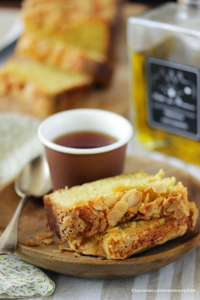Tranches de cake à l'huile d'olive, amande et vanille posées sur une assiette en bois et accompagnée d'une tasse de thé