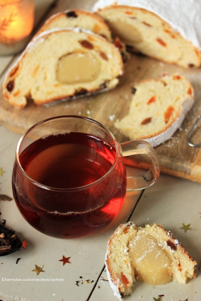 Une tasse de thé pour accompagner une tranche de marzipan stollen vegetal à la pâte d'amandes maison. En second plan, des tranches de stollen et le stollen entier recouvert de sucre glace. 