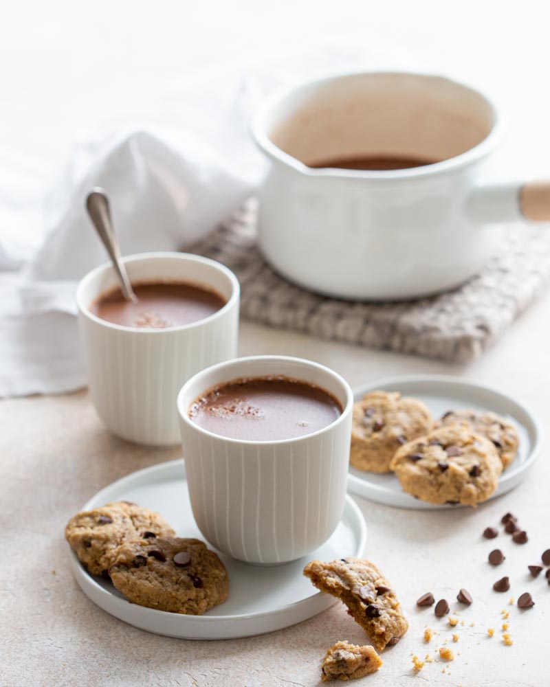 Tasses de chocolat chaud à l'ancienne accompagnées de cookies vegan aux pépites de chocolat et beurre de cacahuète pour un goûter gourmand. 