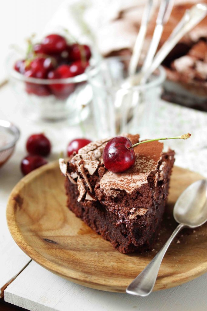 Part de gâteau au chocolat avec une meringue au chocolat servi avec des cerises pour le goûter. 