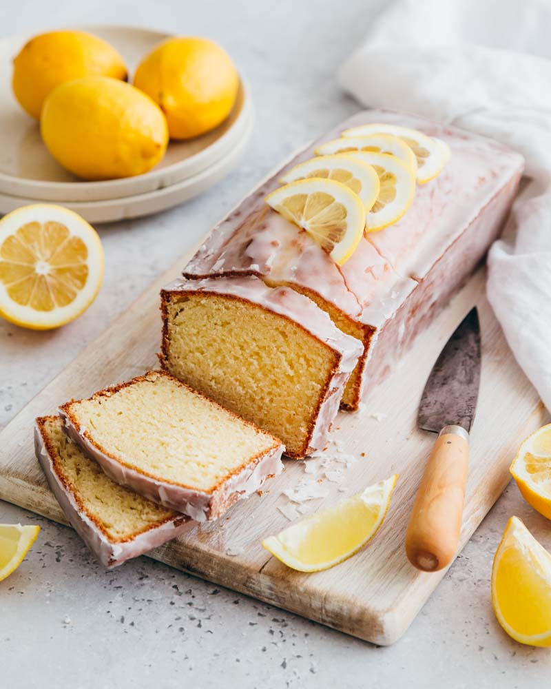 Cake au citron avec un glaçage citron coupé en tranches sur une planche en bois. 