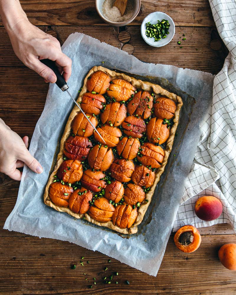 Tarte vegan aux abricots graphique et à la pistache façon réalisée sans moule. Ambiance rustique. 