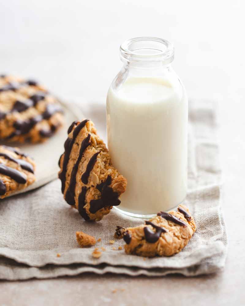Biscuit croustillant à base flocons d'avoine et de poudre d'amandes posé sur une petit bouteille de lait dans une ambiance minimaliste et des couleurs douces