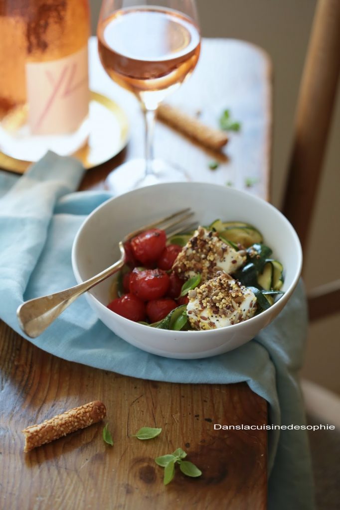 Bowl de tomates cerises et courgettes poêlées avec des cubes de féta enrobés d'un mélange de graines passés à la poêle pour un déjeuner estival.