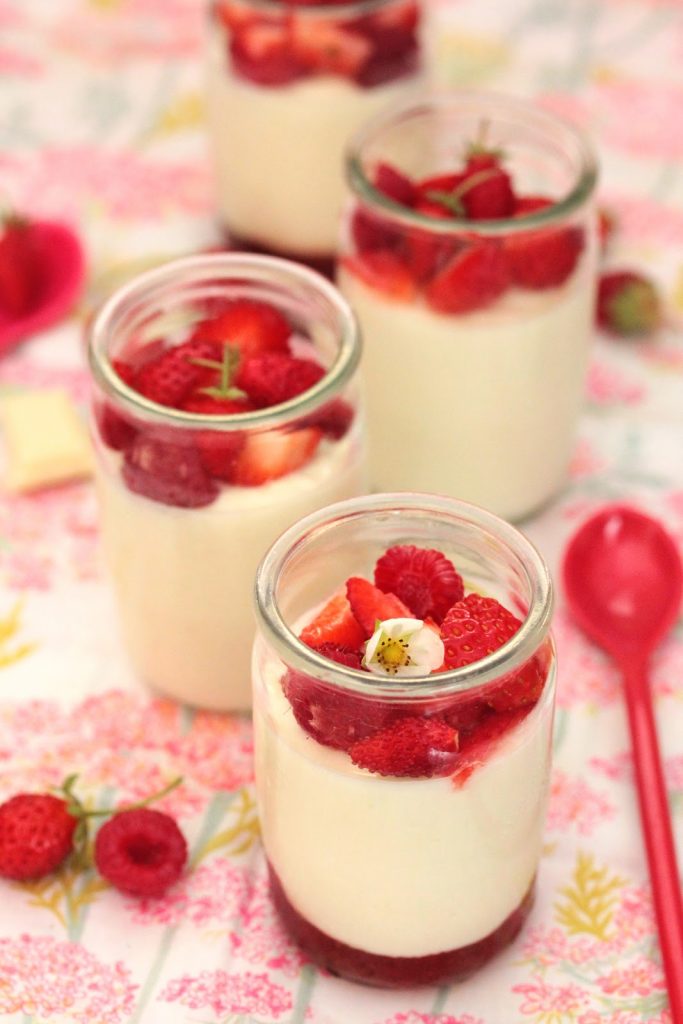 Pots de crème au yaourt onctueux et chocolat blanc fondu et servi avec des fruits rouges. 