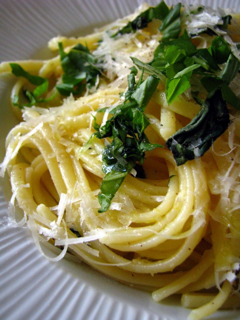 Linguini, cuisinées au citron, au parmesan et à l'huile d'olive avec des feuilles de basilic. Une recette italienne que l'on appelle aussi pâtes au citron. 