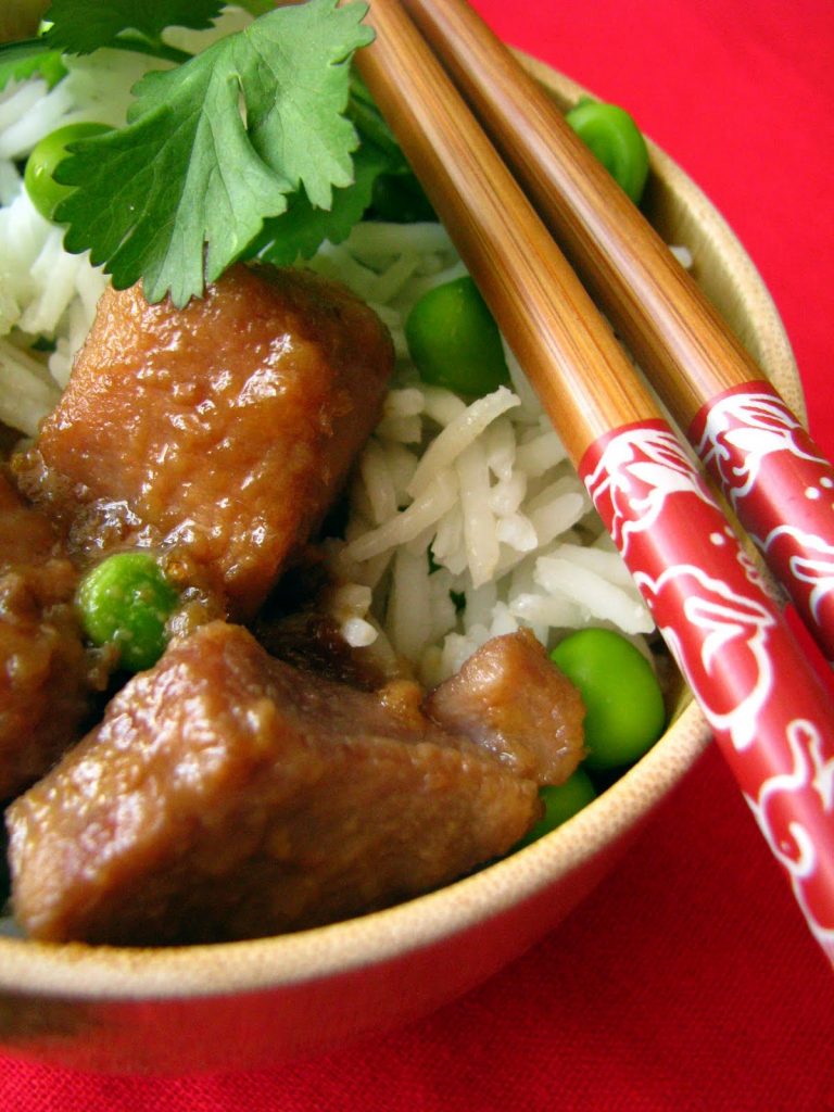 Porc au caramel cuit avec du lait de coco comme en Chine, servi avec du riz et des petits pois.