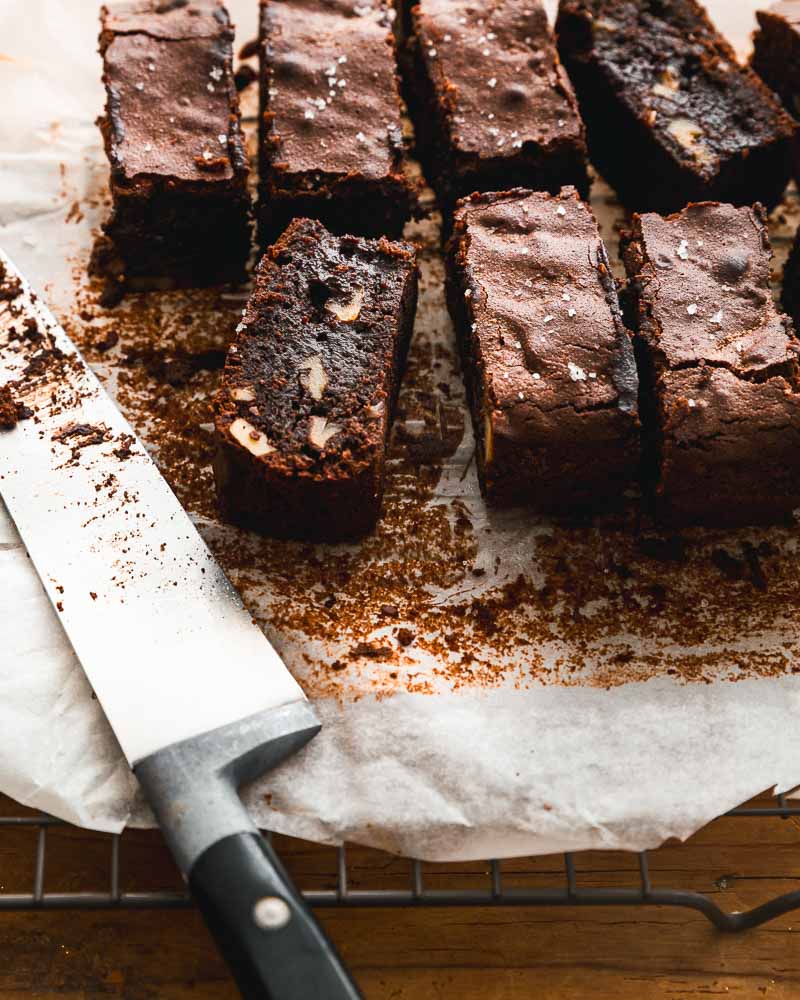 Recette sucrée à l'air Fryer : brownies aux noix découpées en part, posées sur un papier cuisson. 