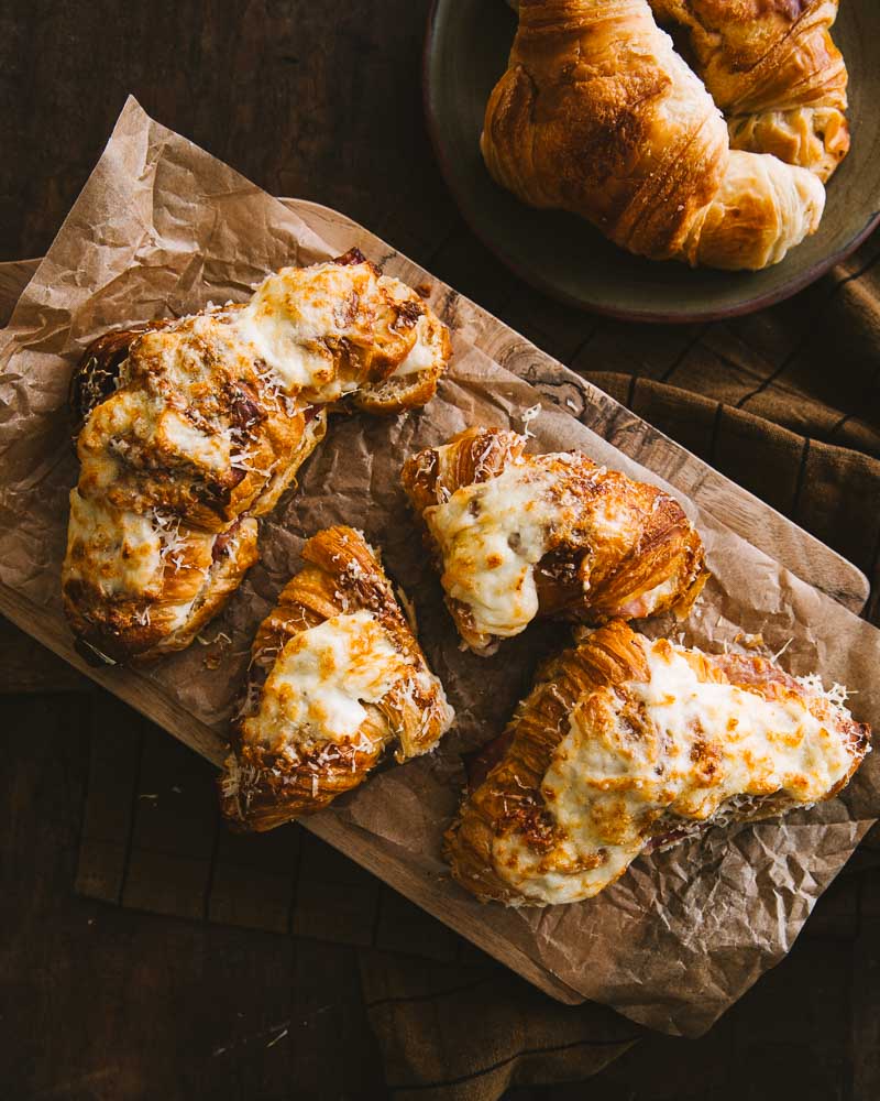 Planche de croissants tout juste sortis sur four garnis de sauce Béchamel, de jambon et de fromage puis gratinés au four. 