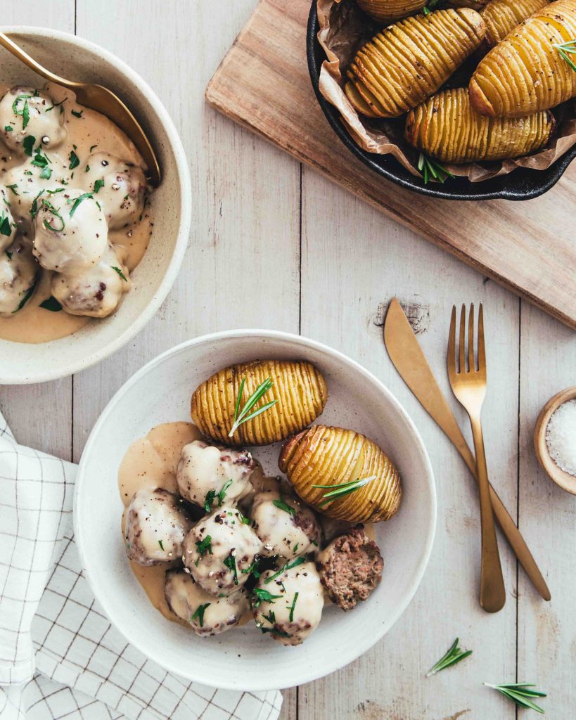 Boulettes de chevreuil à la suédoise servies avec des pommes de terre Hasselback maison dans une ambiance scandinave avec du bois blanc