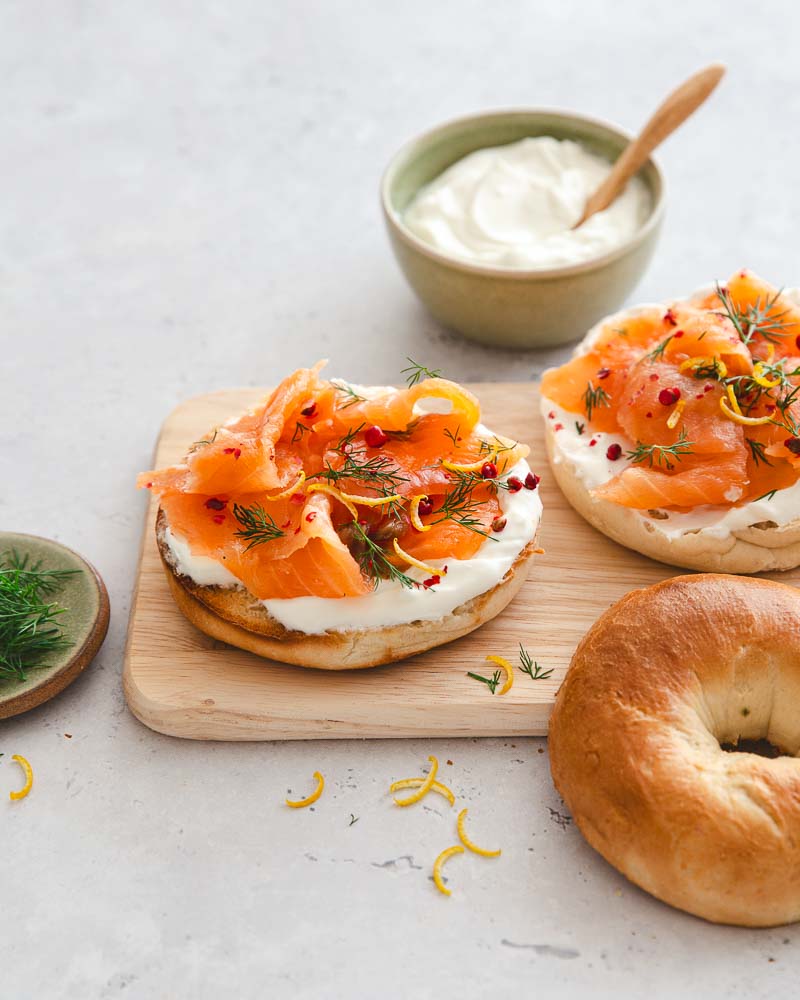 Petite planche en boix où sont posés des bagels au saumon gravlax maison pour le brunch