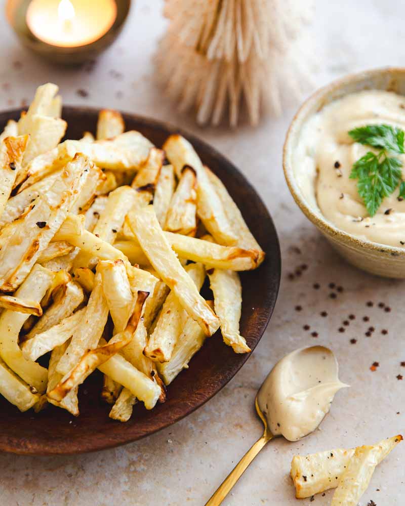 Gros plan sur une assiette de frites de celeri rave à l'Air fryer et d'un bol de mayonnaise à la truffe. A côté, une cuillère dorée rempli de mayonnaise et des frites de céleri.
