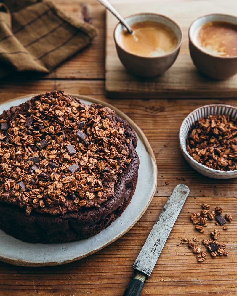 Gâteau au chocolat prêt à être coupé pour le goûter : une pâte sans farine moelleuse garnie d'une ganache onctueuse vegan au tofu soyeux. En décor, du granola au chocolat. 