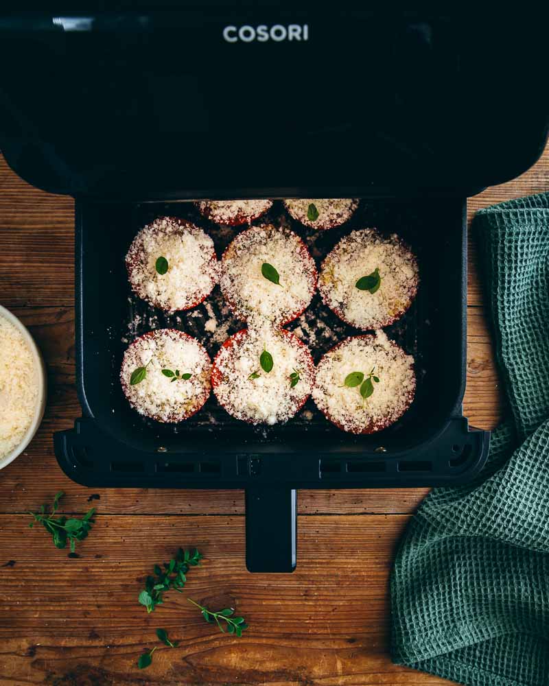 Tomates dans le panier à air fryer recouvertes de pécorino prêtes à la cuisson 