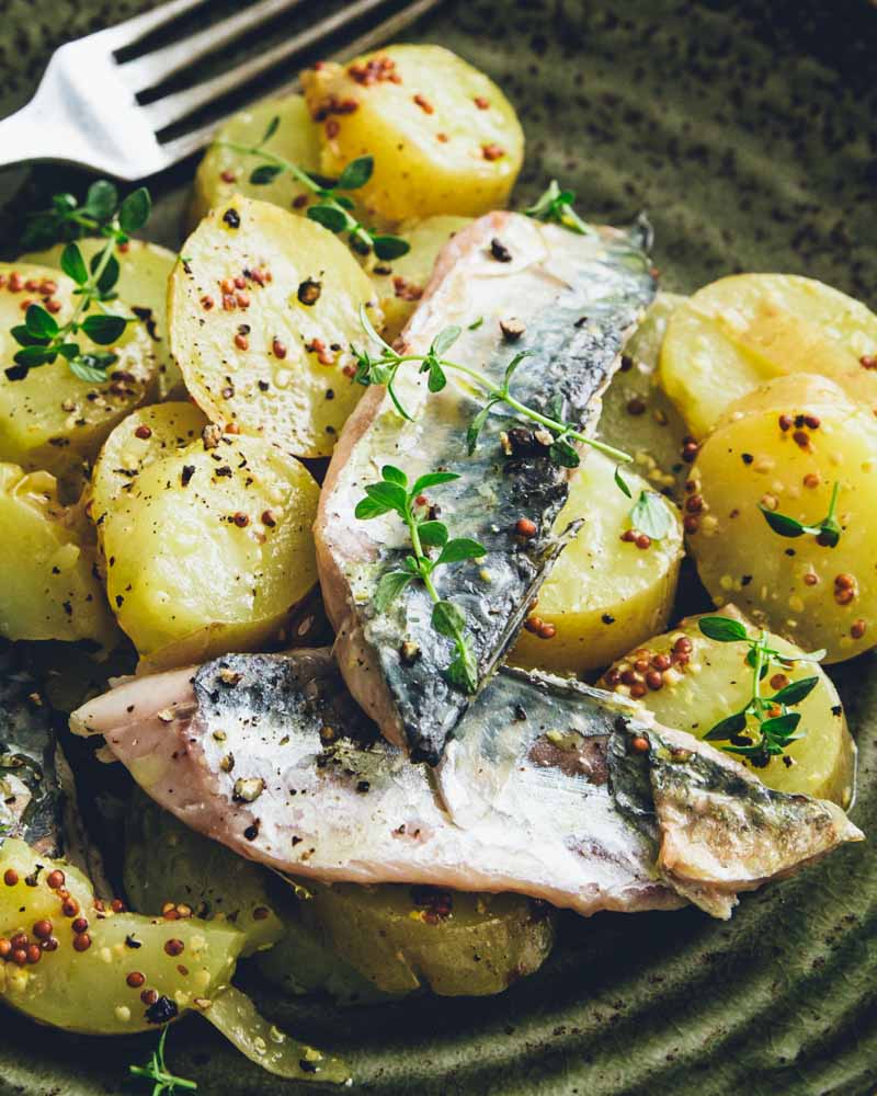 Gros plan sur des pommes de terre en salade avec des filets de maquereaux grillés et sauce moutarde à l'ancienne. Recette nourrissante, économique et IG bas.