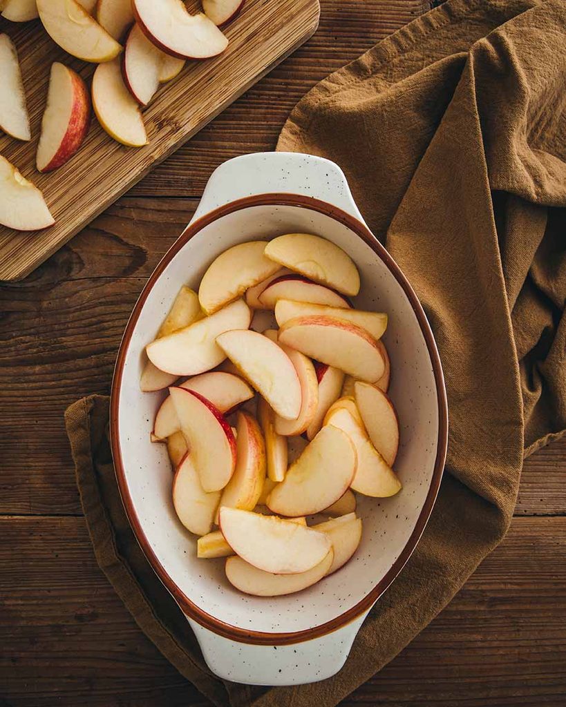 Pommes coupées en quartiers déposés dans le plat allant au four pour la réalisation d'un clafoutis